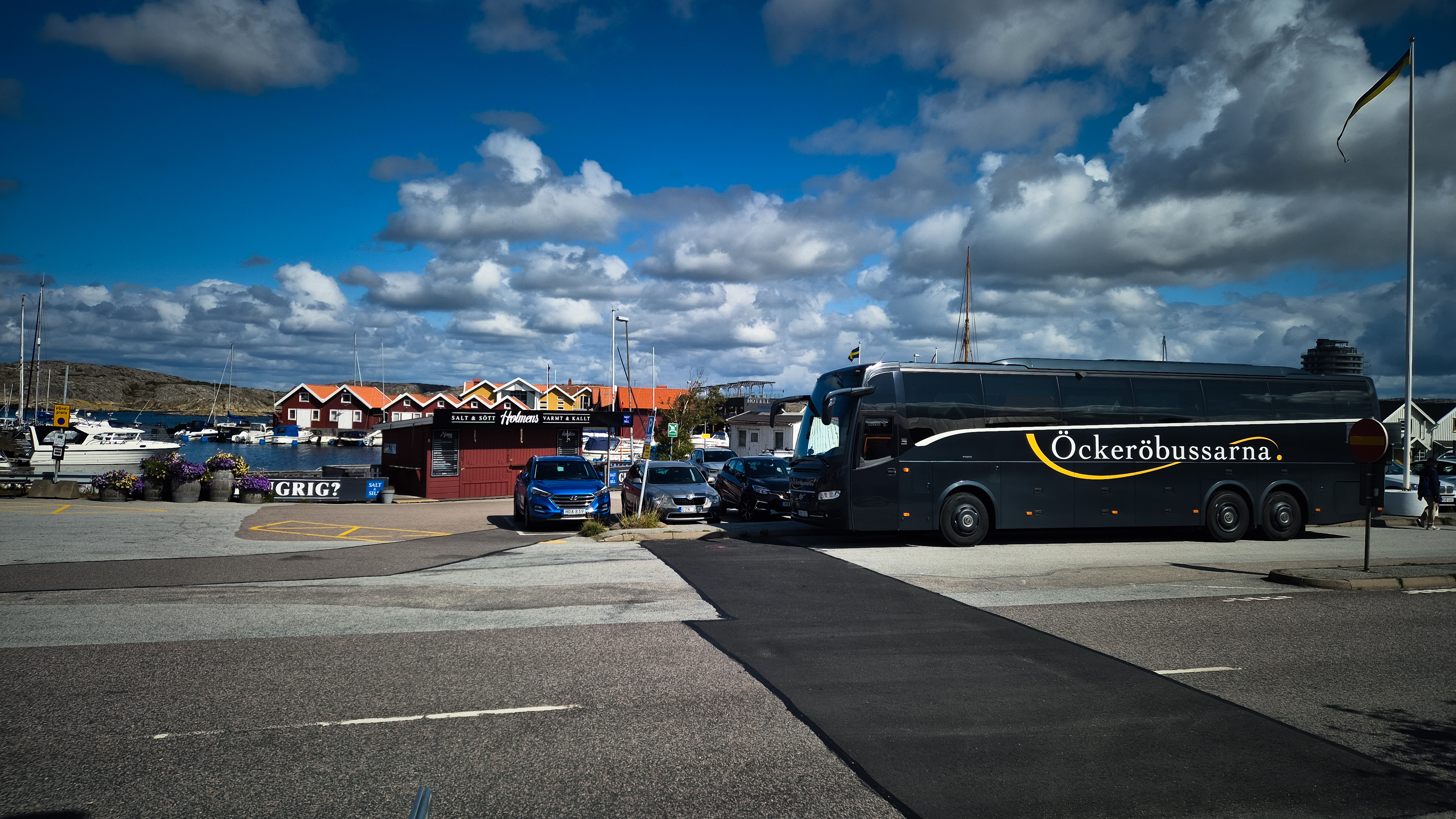 Öckeröbussarnas buss i en hamn med sjöbodar och båtar