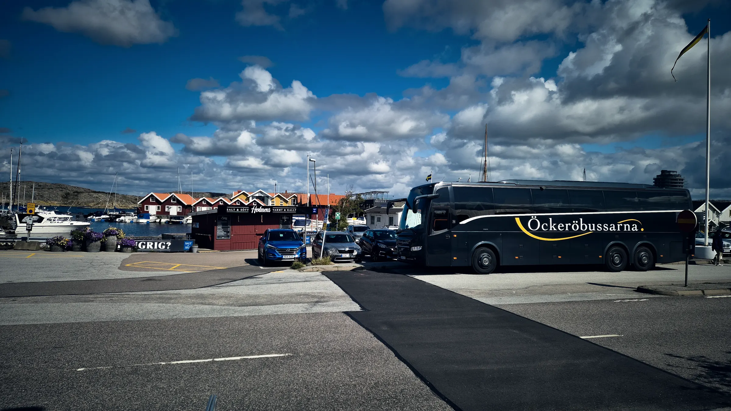 Öckeröbussarnas buss i en hamn med sjöbodar och båtar