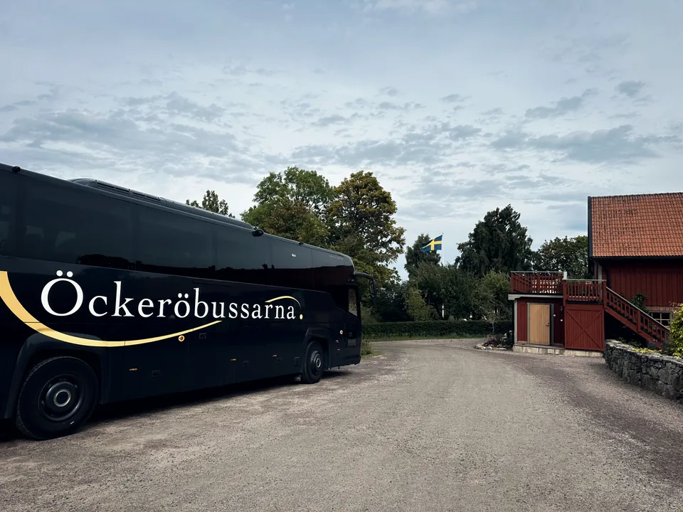 Öckeröbussarnas buss vid ett rött trähus på landet